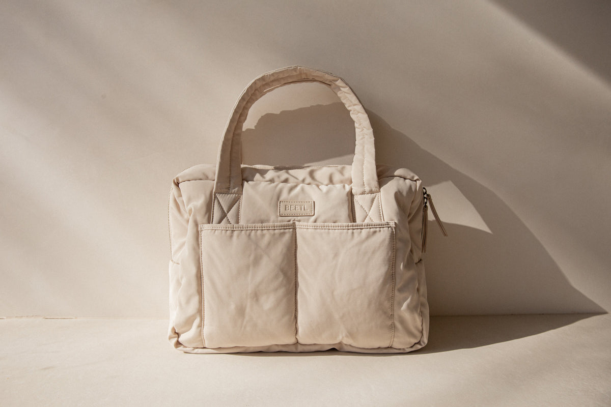 Cream BEETL Baby Bag with multiple compartments and adjustable straps, designed for convenient carrying.