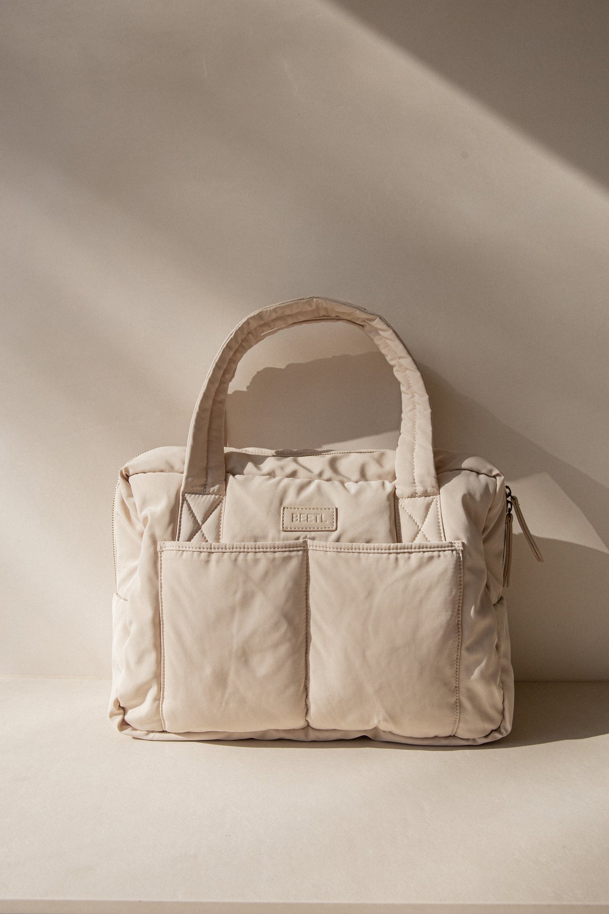 Cream BEETL Baby Bag with multiple compartments and adjustable straps, designed for convenient baby essentials storage.